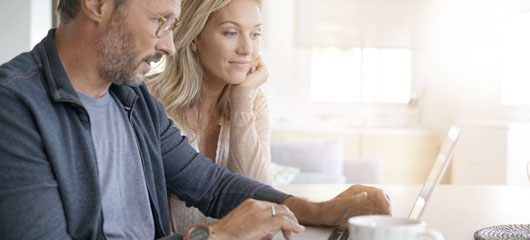 pareja madura mirando un portátil