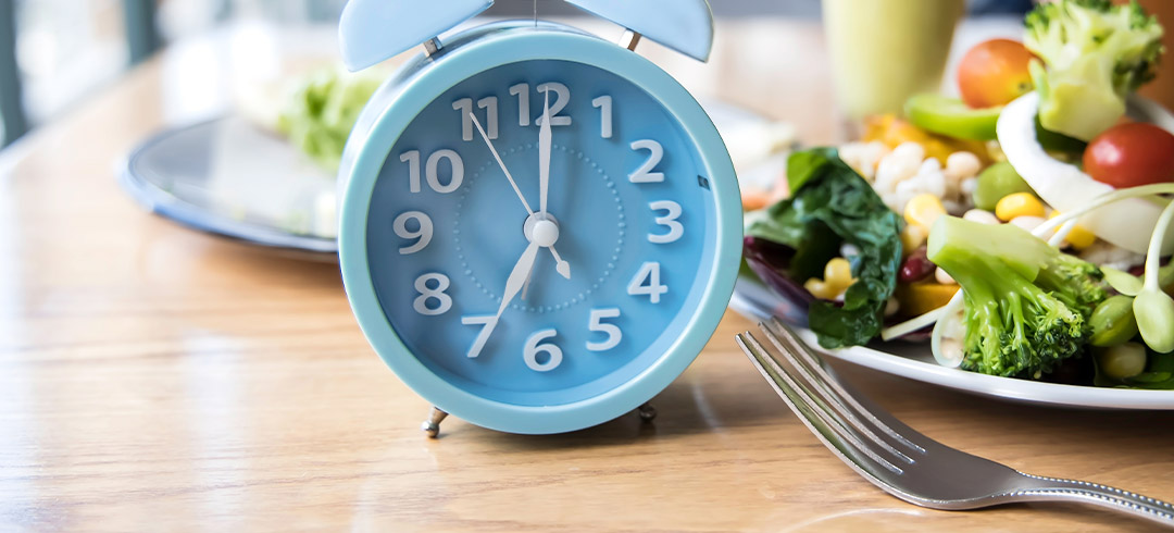 Reloj despertador sobre una mesa con comida